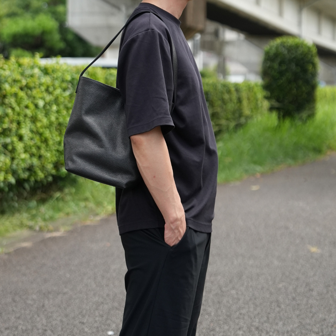 ブラックのレザーバケットバッグを着用したメンズスタイル ミニショルダーバッグのミニマルなコーディネート