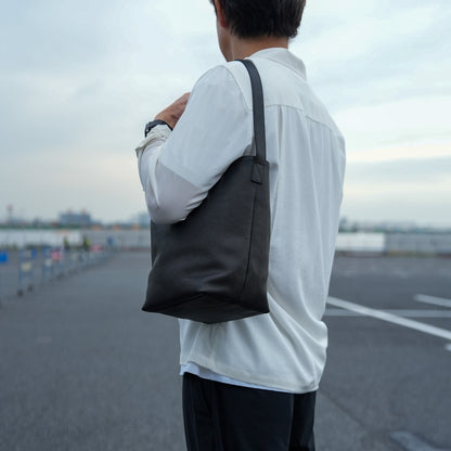 レザーバケットバッグを持ったメンズの日常スタイル シンプルで洗練されたミニショルダーバッグ