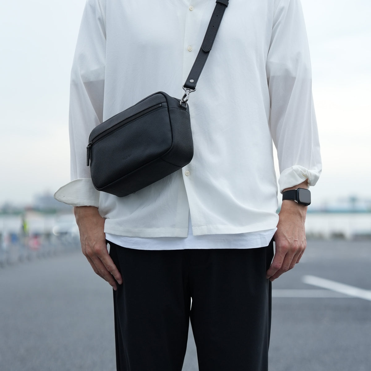 本革のカメラバッグを斜め掛けしたメンズコーディネート シンプルでミニマルなデザイン